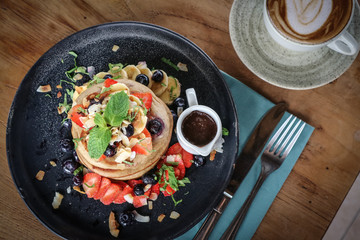 Pancakes with banana, blueberries, strawberries and chocolate sauce