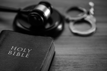 Black and white image of a gavel, handcuffs and a bible