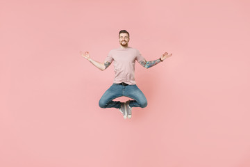 Fototapeta na wymiar Smiling young tattooed man guy in pastel casual t-shirt posing isolated on pink background studio. People lifestyle concept. Mock up copy space. Jumping hold hands in yoga gesture relaxing meditating.