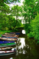Colorful boats in peaceful river surrounded by lush green scenery in Ireland