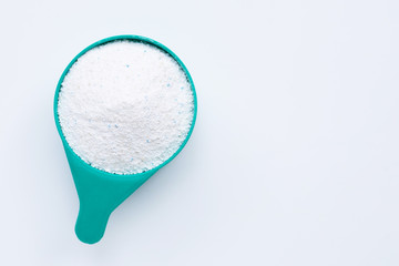 Measuring scoop with laundry powder on white background. Copy space