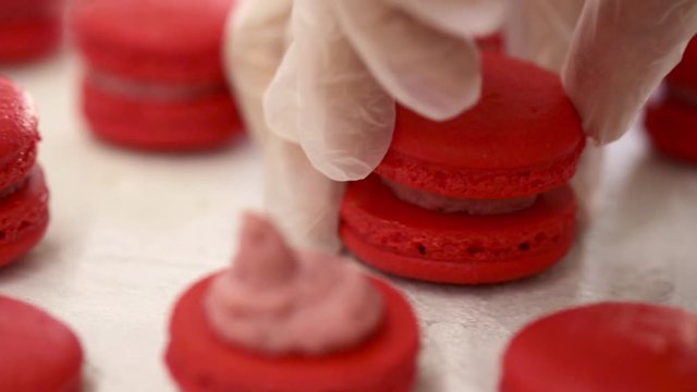 Making Red Macaroons. Close up shot of connecting two halves of macaroons with strawberry cream