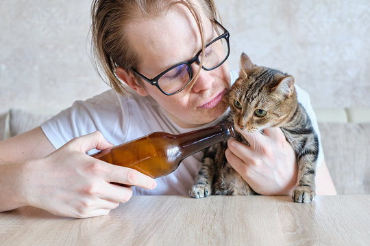 A drunk man offers a drink to his cat.