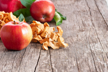Dried sliced apple fruit with ripe fresh red apples on wooden rustic background, homemade dry fruit concept