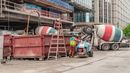 Construction workers and cement trucks working on a highrise in the city