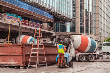 Construction workers and cement trucks working on a highrise in the city