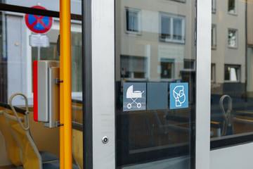 Selected focus at face mask covering mouth and nose symbol on blue sign on glass of public transportation's window door in Germany during epidemic of COVID-19 virus and German face mask regulations.