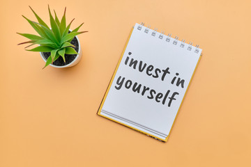 Concept invest in yourself notepad inscription on an orange table.