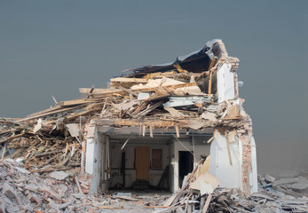 Demolished house under big heap of debris, but some interior still visible through torn down wall