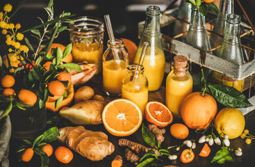 Immune boosting vitamin health defending drink. Turmeric, ginger and citrus juice shots in bottles and fresh ingredients over concrete kitchen counter, close-up. Pure vegan Immunity system booster