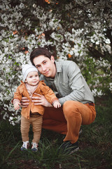 A father and a little boy are having fun near the cherry blossom trees.