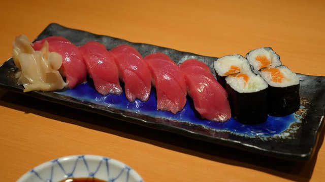 Tasty tuna sushi on small plate with roll pieces, close up shot of traditional Japanese meal served at Tokyo restaurant. Fresh fish meat pieces on rice, popular nigirizushi