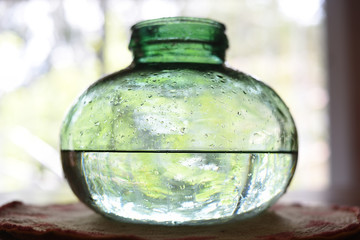Drops in green glass vase, half full, half empty concept.