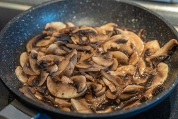 Thinly sliced fresh raw mushrooms are fried in a pan close-up. Healthy diet