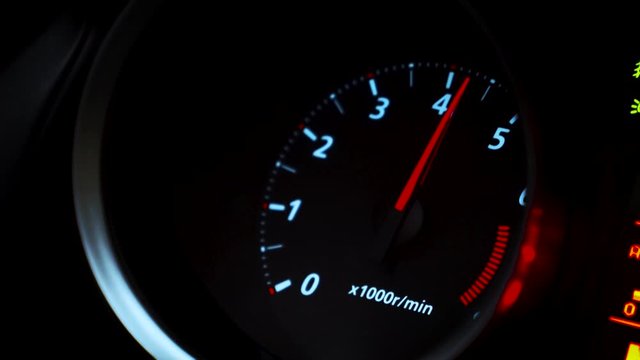 Tachometer of a modern car reacts to hard accelerations by the driver, who is reflected in the glass. Footage. Motion concept, close up video.