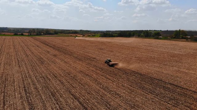 green tractor in the field sows corn, aerial image