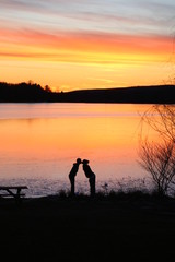 Obraz premium silhouette of man and woman kissing on the beach at sunset beside a lake