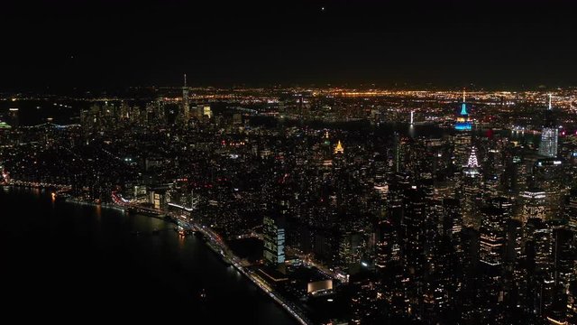 Aerial shot of New York City above East river showing Manhattan by night