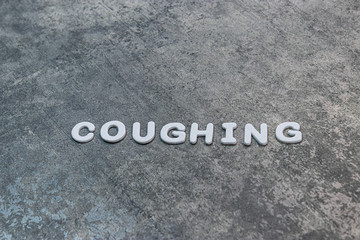 coughing written out on gray background with white lettering