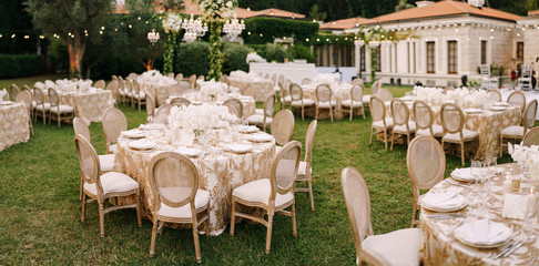 Wedding dinner table reception. Elegant tables for guests with cream tablecloths with patterns, on...