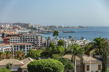 Obraz premium Las Americas, Tenerife, Spain - September 25, 2018: Panoramic view of very popular holiday resort on the island with clubs, hotels and bars. Coast with beaches and clear blue sky above the horizon