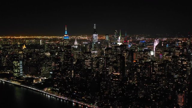 Aerial shot of New York City above East river showing Manhattan by night