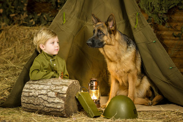 a boy stands with a shepherd in uniform. 