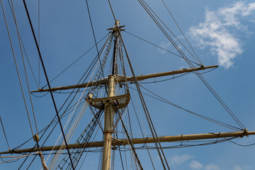 Detail view of an old tall ship mast and rigging, old wooden sailing vessel with rigging lines...