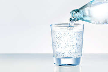 Pouring water from bottle into glass with place for text. Mineral water.