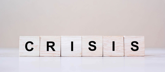 Obraz premium wooden cube blocks with CRISIS text on table background. Coronavirus pandemic, risk, fall Business, unemployment, Economic recession and Bankrupt concept