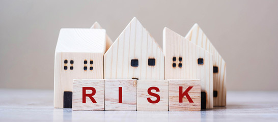 RISK cube blocks with wooden house model on table background. Coronavirus pandemic, fall Business, investment, Crisis, Economic recession, Developer, Real Estate and Property concept