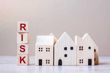 RISK cube blocks with wooden house model on table background. Coronavirus pandemic, fall Business, investment, Crisis, Economic recession, Developer, Real Estate and Property concept