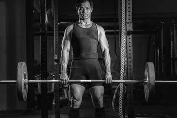 Fototapeta na wymiar asian athletic strong man having workout and bodybuilding with weight lifting deadlift style in gym and fitness club in dark tone
