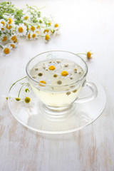 glass cup of hot chamomile tea on a light wooden background. herbal drink