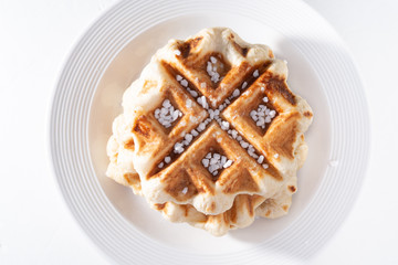 belgian waffle over a white plate with sugar