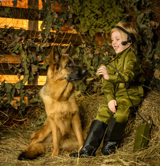 a boy stands with a shepherd in uniform. 