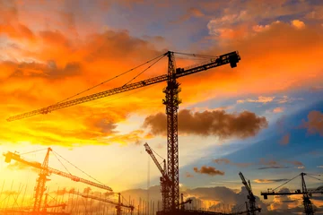 Schilderijen op glas Tower crane and building construction site silhouette at sunrise. © ABCDstock