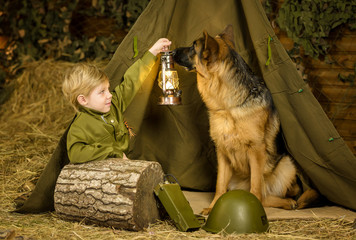 a boy stands with a shepherd in uniform. 