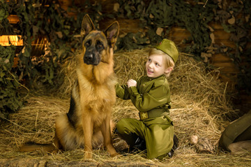 a boy stands with a shepherd in uniform. 
