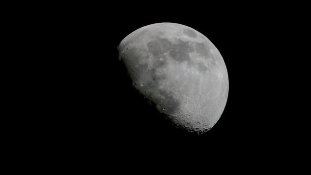 Waxing Moon rising upwards at more than half full moon with craters in space Real footage of the moon (NOT animated)