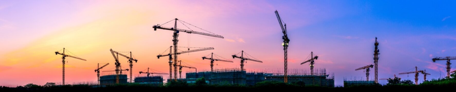 Tower crane and building construction site silhouette at sunrise.panoramic view.