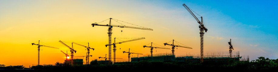 Tower crane and building construction site silhouette at sunrise.panoramic view.