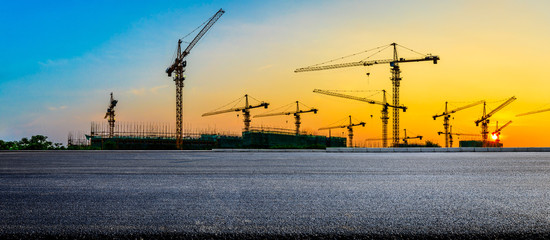 Empty asphalt road and construction site landscape at sunrise.