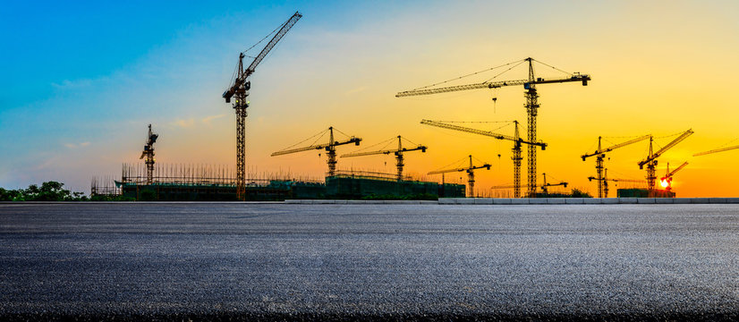 Empty asphalt road and construction site landscape at sunrise.