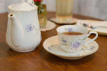 Teapot and cup of tea on wooden table. vintage style of tea set