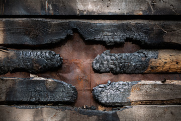 Barn wood wall after fire. Embers, charred and burned wooden boards. Arson and intentional wrecking of private property.