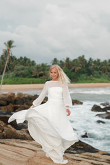 Fototapeta na wymiar Bride is dancing at the beach. Happy bride in wedding dress dancing on the beach