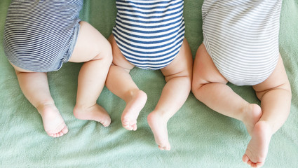 Newborn triplets lie on a stomach on a blanket - 346350601