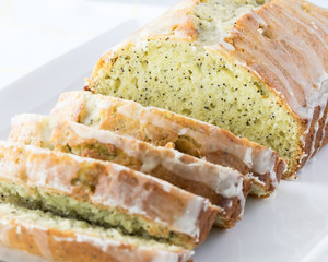 A close up view of a glazed lemon poppy seed loaf cut into slices.