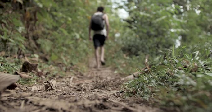 Backpacker in slippers walks along a trail in the forest